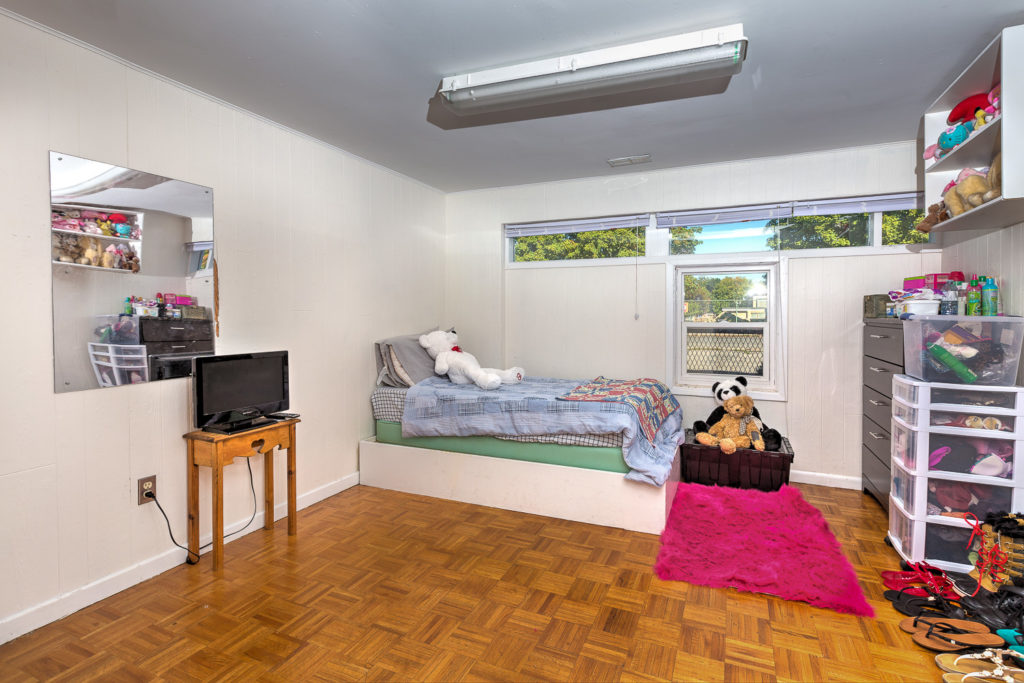 Interior shot of 49/51 Chapman Avenue. In this shot, a warm bedroom with stuffed animals, storage units and bed.